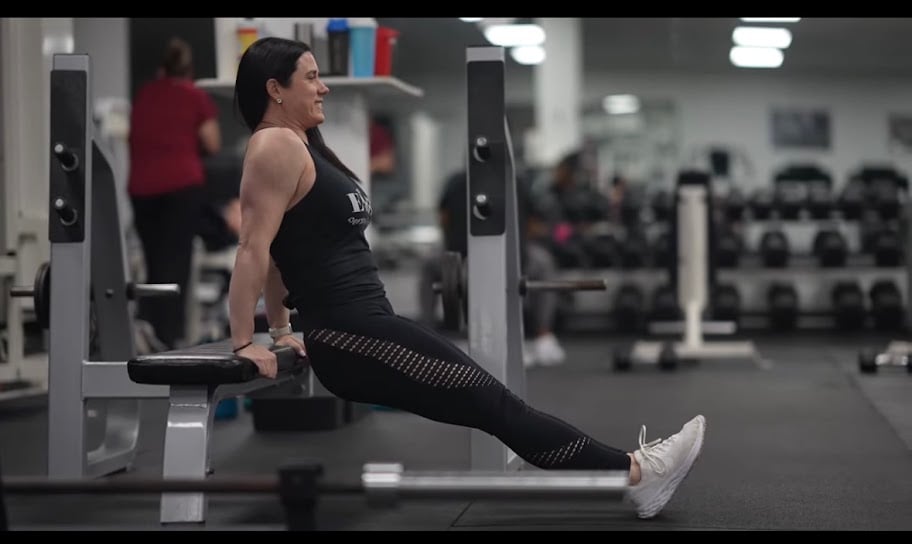 Female fitness coach Jennifer Schulze helping a woman perform strength training exercises, demonstrating the importance of building muscle and confidence after 40.