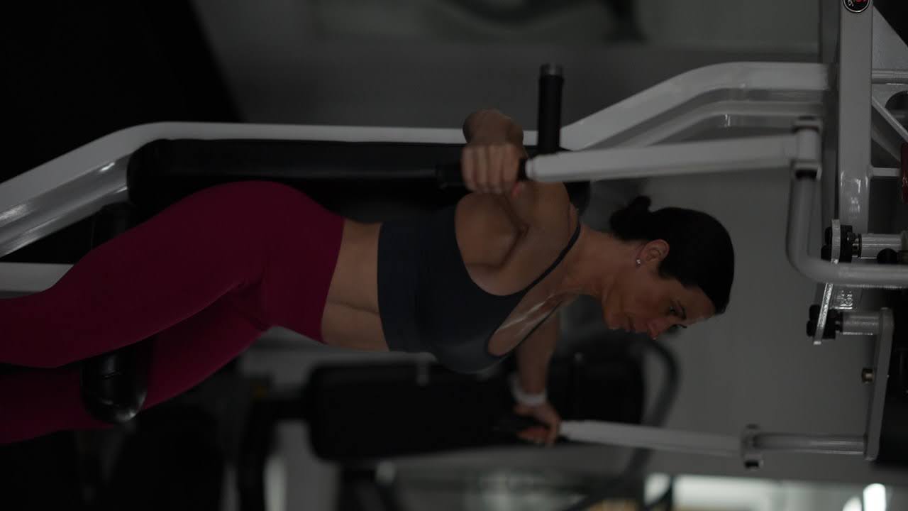 Female fitness coach Jennifer Schulze helping a woman perform strength training exercises, demonstrating the importance of building muscle and confidence after 40.